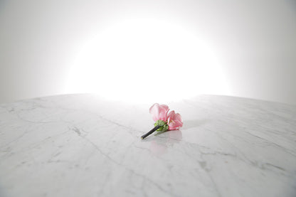 Kate Hill Flowers – pink spray rose buttonhole flowers with black-taped stem and pearl pin on a marble table setting.