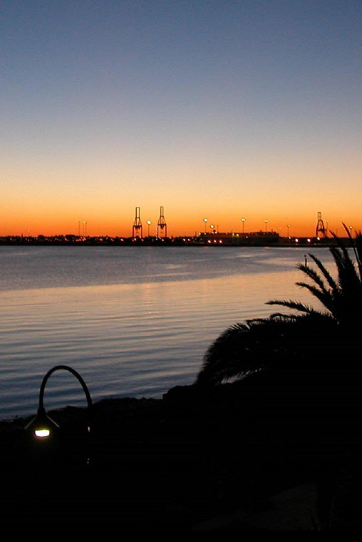 Sunset over Port Melbourne with industrial cranes in the distance.