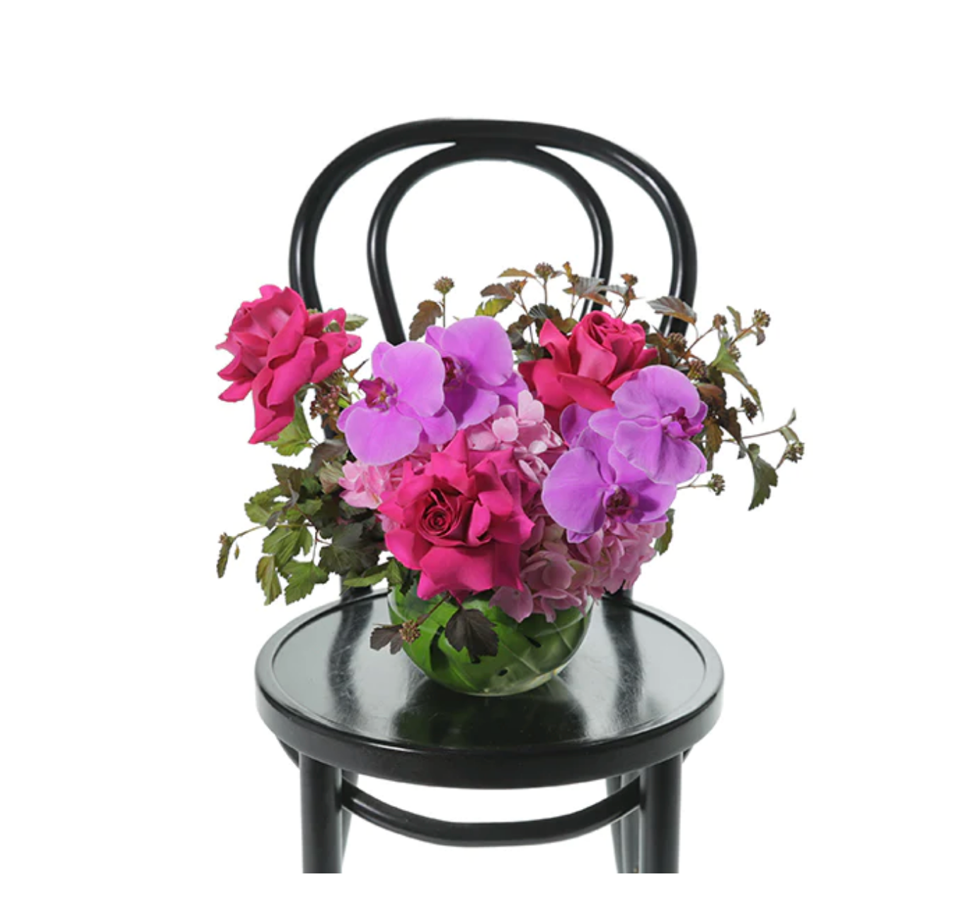 Pink and purple ball vase floral design on black bentwood chair with roses and orchids