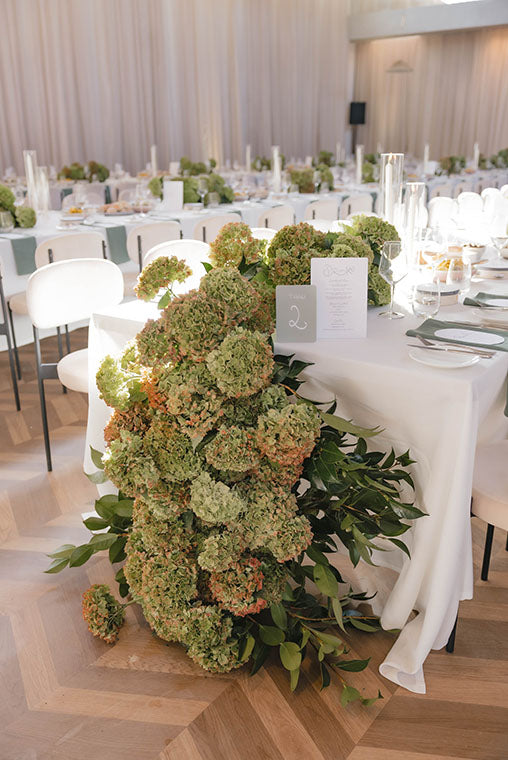Decorative Melbourne wedding flowers on a table with a formal event setting in the background.