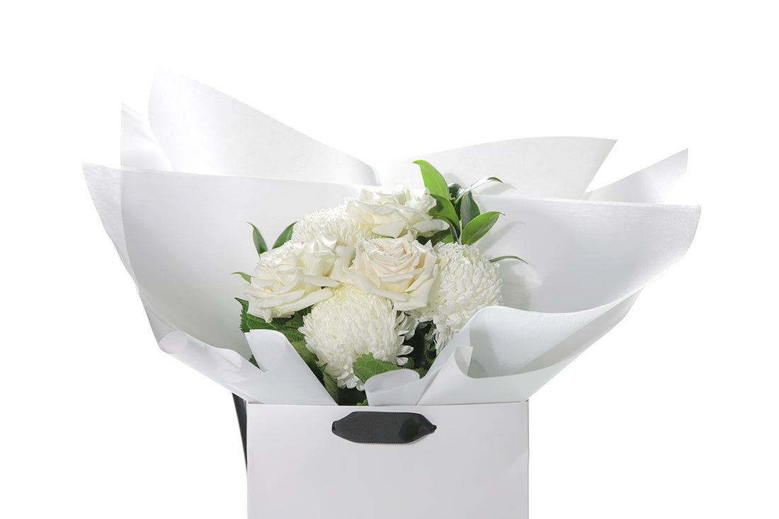Kate Hill Flowers – small white sympathy posy of roses and chrysanthemums in a water-filled gift bag.