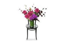 Wide image of vase design. A large mixed pink, magenta, jewel toned vase design sitting on a black bentwood chair. Large vase design sitting on chair with white background.