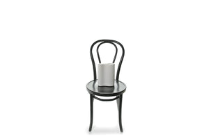 A 22cm White ceramic wave vase sitting on black bentwood chair with white background. 