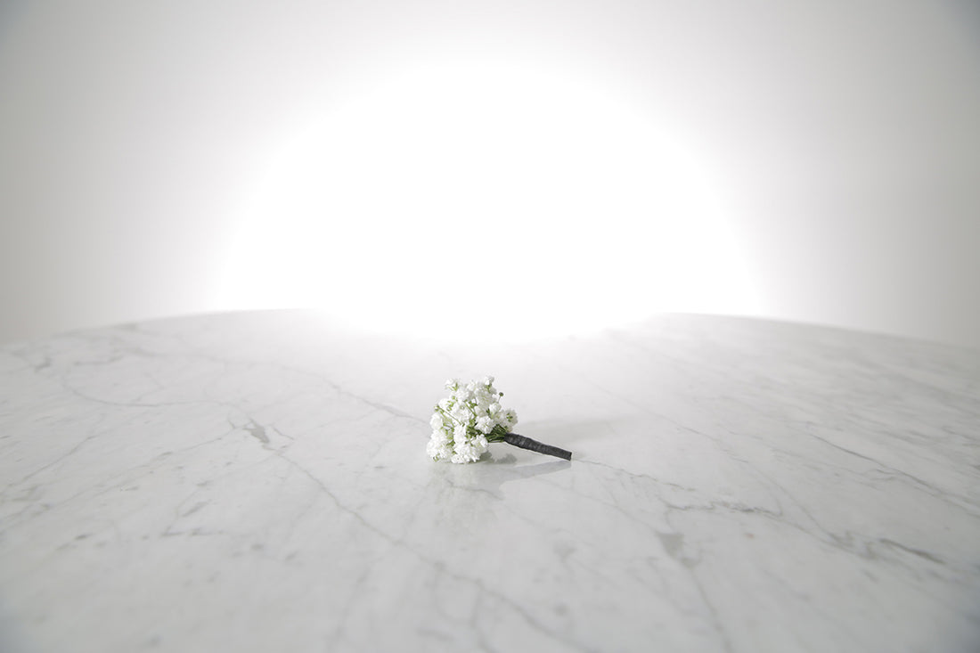 White flower boutonniere buttonhole flowers on a marble surface with a white background