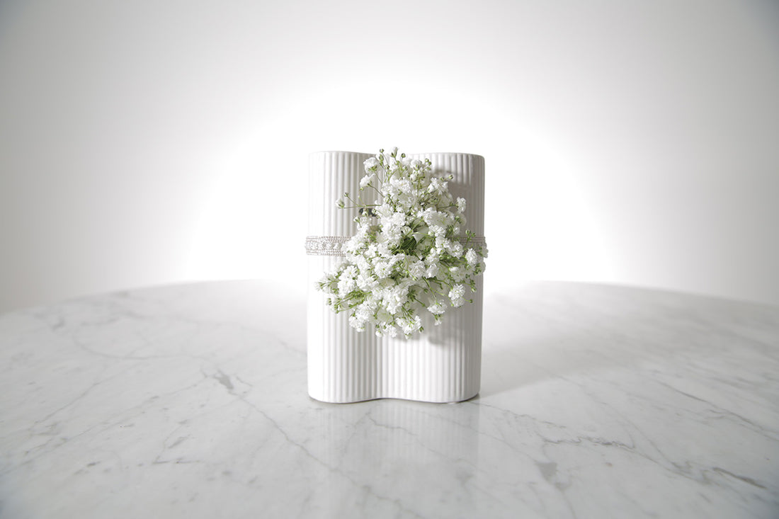 Kate Hill Flowers white gypsophila wrist corsage on a silver elastic wristlet, boxed and ready to wear, displayed on a marble surface.
