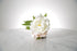 Kate Hill Flowers artificial white peony and blush hydrangea wrist corsage on silver elastic wristlet, displayed on a marble table with a white background.