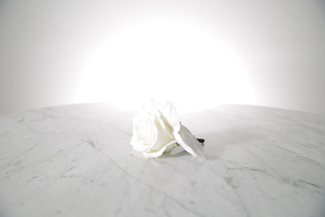 White rose buttonhole on a marble surface with a light grey background