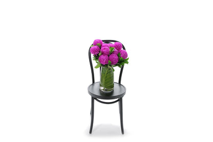 ARIA hot pink disbuds in a tapered glass vase lined with monsteria