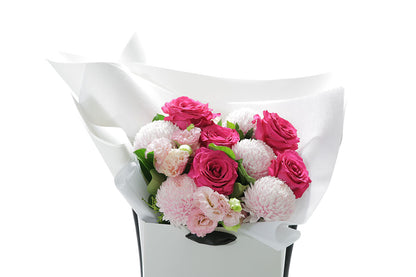 Close up of HARPER Bouquet of pink and white flowers wrapped in white paper on a white background