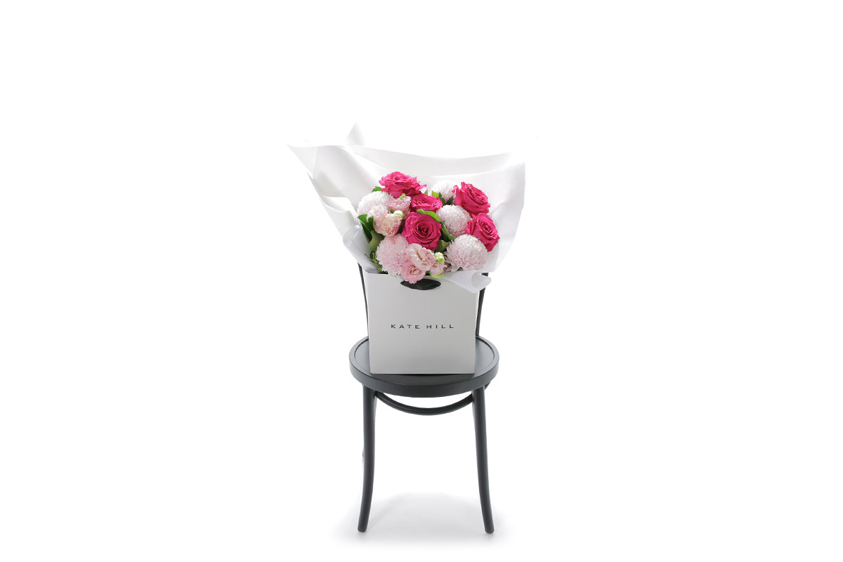 HARPER Floral arrangement in a box on a black chair with a white background by Kate Hill Flowers
