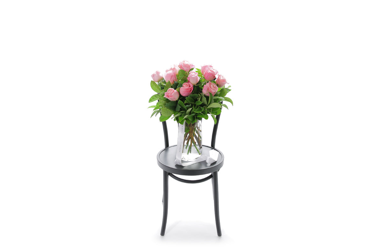 HERMOSA watermelon roses in a tapered glass vase lined with monsteria