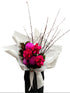 A Melbourne florist wearing black holding a bouquet of flowers with hot pink flowers wrapped in white paper against a white wall.