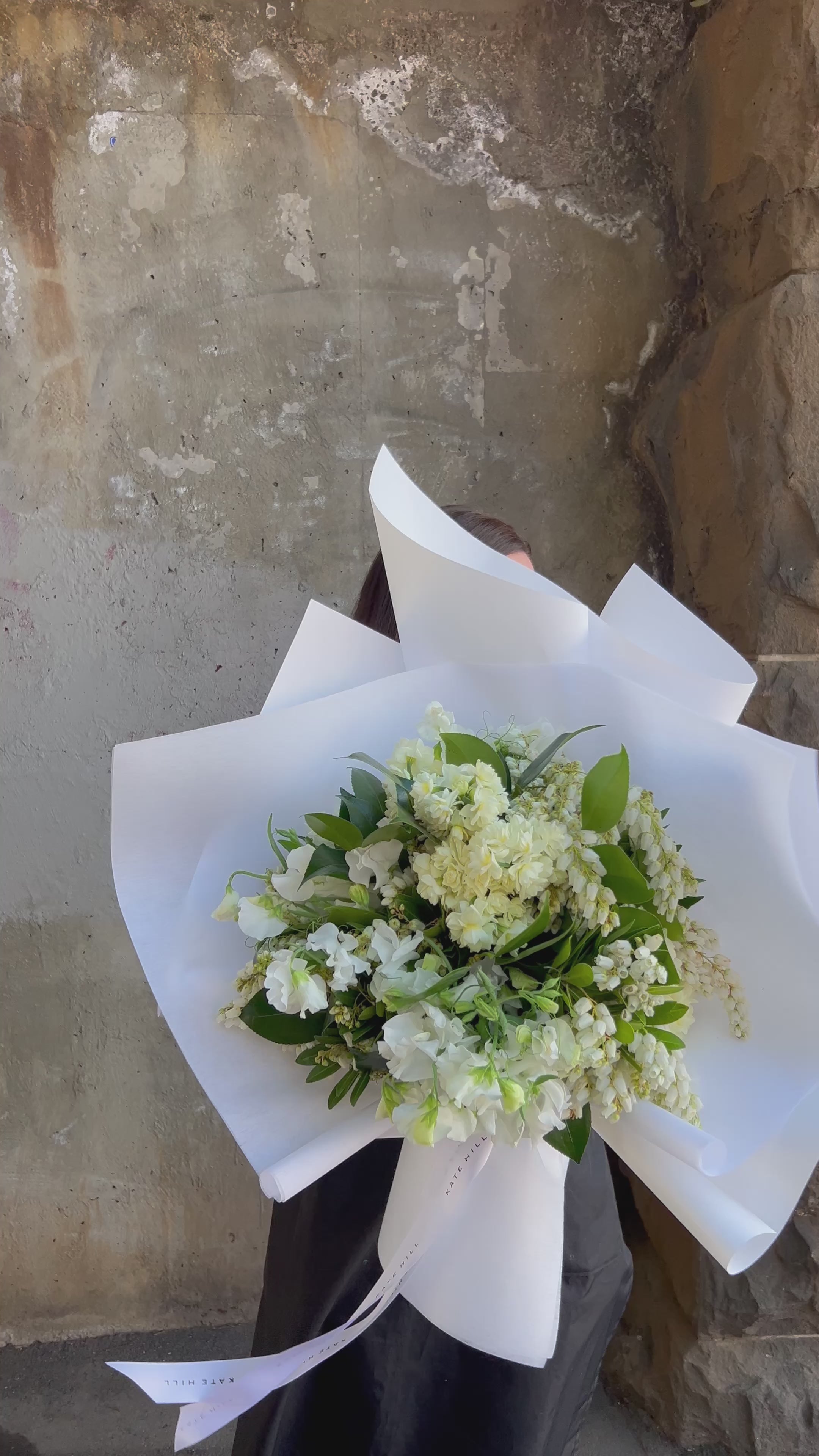 Video of white and green spring bouquet, held by florist. White and green spring bouquet of sweetpea, erlicheer and clethra, beautofully wrapped in white signature wrapping.
