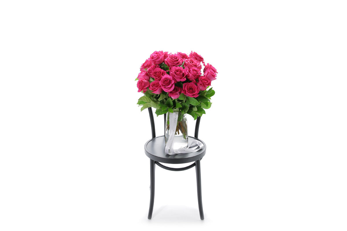 SASKIA 20 hot pink roses in a tapered glass vase lined with monsteria