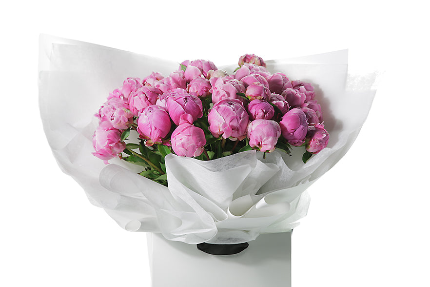 Best selling Peony Rose bouquet featuring 15 stems of pink peonies (flower only). Bouquet of peony roses presented in white signature wrapping and placed into Kate Hill Flower Bag. Close up image of the Peony Rose bouquet.