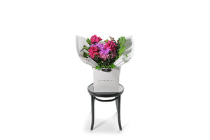 Wide image of ARIA bouquet. A bright pink, magenta and soft pink gift bouquet named ARIA beautifully gift wrapped in our Kate Hill signature wrapping. Gift bouquet is presented into our Kate Hill flower bag to ensure the bouquet remains fresh in water. ARIA bouquet is sitting on a black bentwood chair.