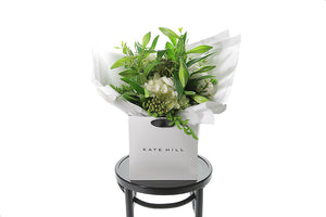 BETH Christmas Bouquet is packed full of festive and fragrant flowers that may include Christmas or Longiflorum Lilies, Hydrangeas, Berries and seasonal festive foliages (Spruce, Oak, Beech, Ivy Berry).  Our BETH Christmas Bouquet is delivered beautifully gift wrapped in Kate Hill Flowers signature wrapping and placed into our Kate Hill Flower Bag. Bouquet bag is sitting on a black bentwood chair so you can see whats inside the bouquet.