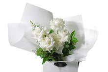 Close image of the BLANCA rose flower bouquet. You can see the 6 roses, foliage and beautiful wrapping.Large white rose bouquet displaying 6 stems of reflexed roses and green seasonal foliage. Presented beautifully in white signature wrapping and in Kate Hill Flower Bag.