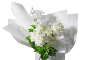 Chic, large and luxe bouquet featuring pure white phalaenopsis orchid stems, white reflexed roses and seasonal green foliages. Gift bouquet presented in Kate Hill Flower Bag. Close up image of the bouquet.
