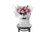 Beautiful pink peony rose bouquet displaying 15 stems of pink peony roses and green seasonal foliage. Bouquet of peony roses presented in white signature wrapping and placed into Kate Hill Flower Bag. Bouquet bag sitting on a black bentwood chair.